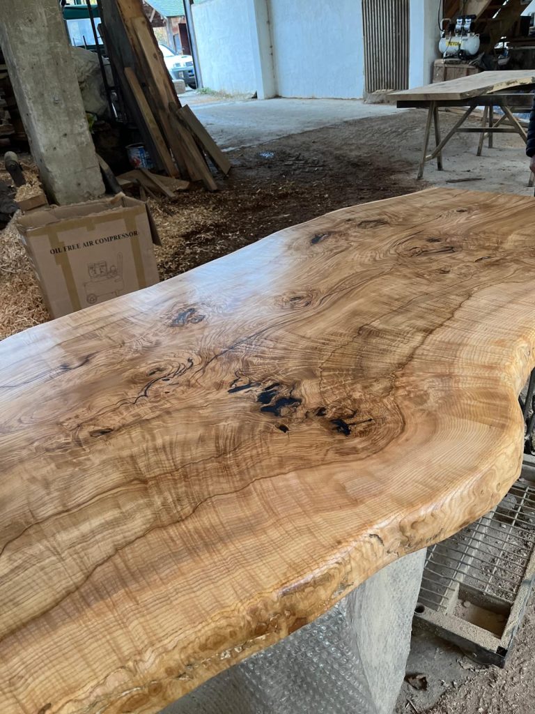 Grand plateau en bois clair aux nervures ondulées, séchant en atelier