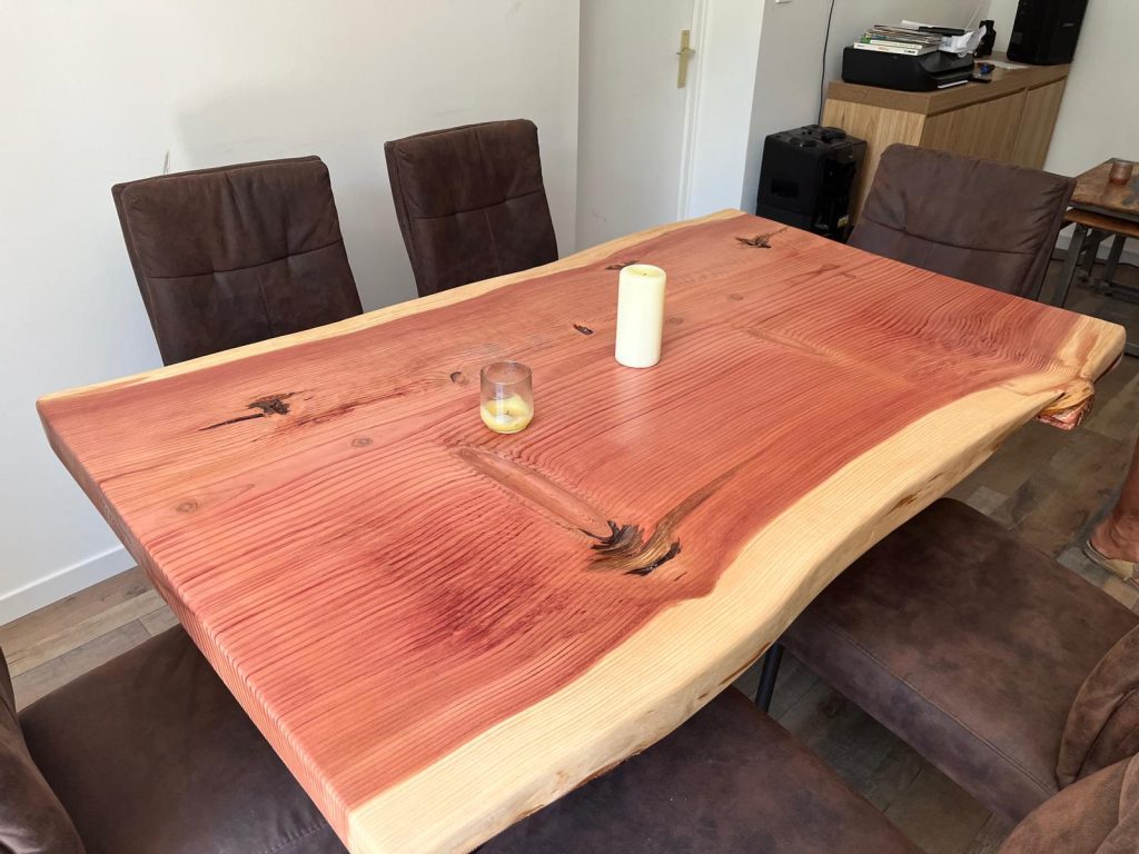 Table de salle à manger en cèdre teinté rouge avec bord naturel, installée chez le client